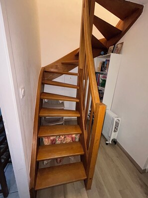 A wooden staircase with a white radiator and a bookshelf in the background.