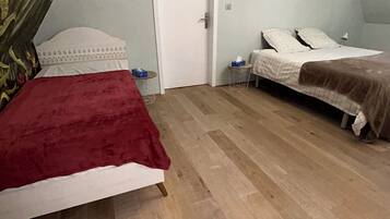 Une chambre avec deux lits, une porte blanche et un plancher en bois.