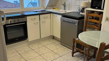 A kitchen with a stove, oven, sink, and a microwave. There is a dining table with chairs.