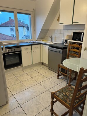 A kitchen with a stove, oven, sink, and a microwave. There is a dining table with chairs.