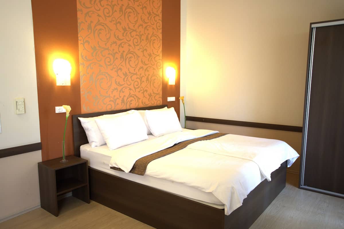 A neatly made bed with white linens, two bedside tables, and wall-mounted lamps.