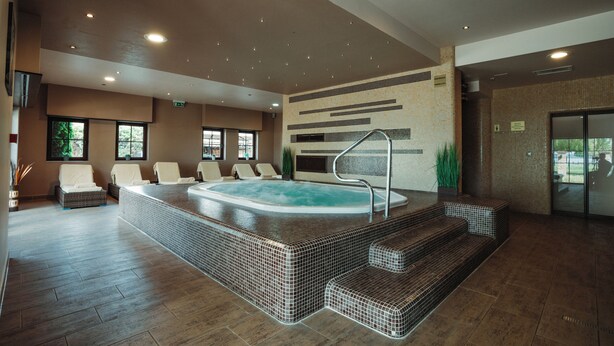 Un espace spa comprenant un jacuzzi, des sièges et un mur recouvert de carreaux.