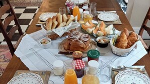 A breakfast table set with bread, pastries, fruits, and beverages. - Chateau de Bellefontaine (Flagy)