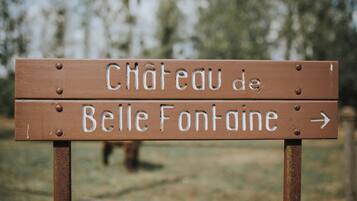A wooden sign with the text "Château de Belle Fontaine" and an arrow pointing to the right.
