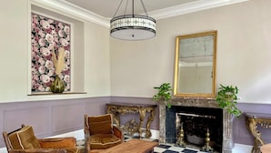 A room with a checkered floor, a fireplace, a mirror, and a floral painting on the wall. - Chateau de Bellefontaine (Flagy)