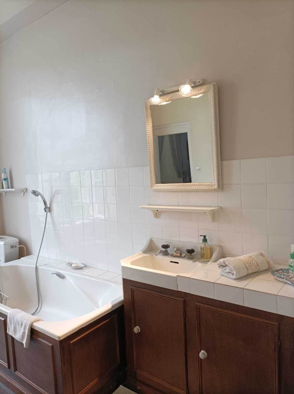 Een badkamer met een bad, een wastafel met een spiegel erboven en een douche.