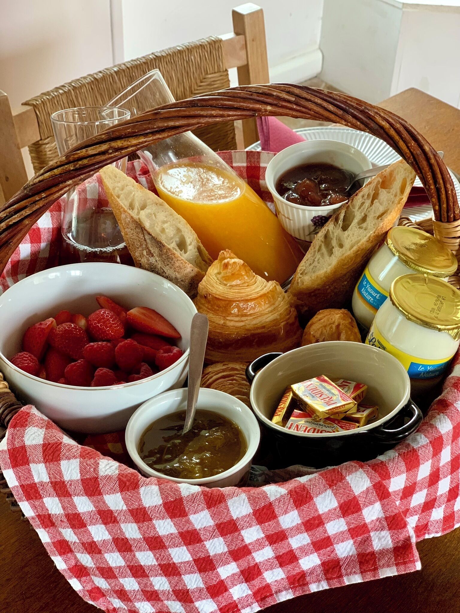 Una bandeja de desayuno con pan, fruta, mermelada, miel y una botella de leche.