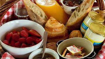 Una bandeja de desayuno con pan, fruta, mermelada, miel y una botella de leche.