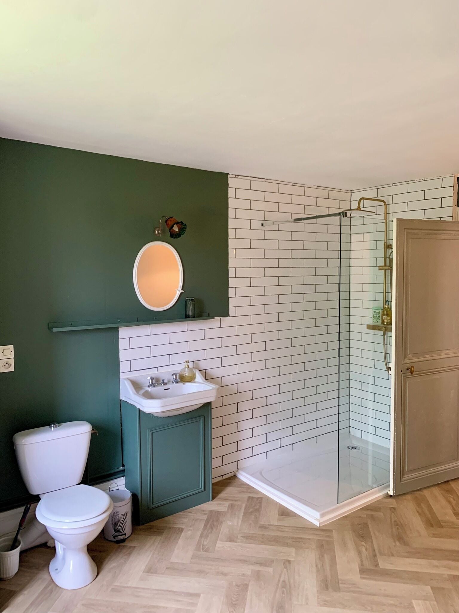 Et badeværelse med toilet, vask og glasvægsbruser.