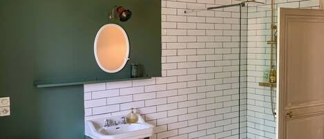Et badeværelse med toilet, vask og glasvægsbruser.