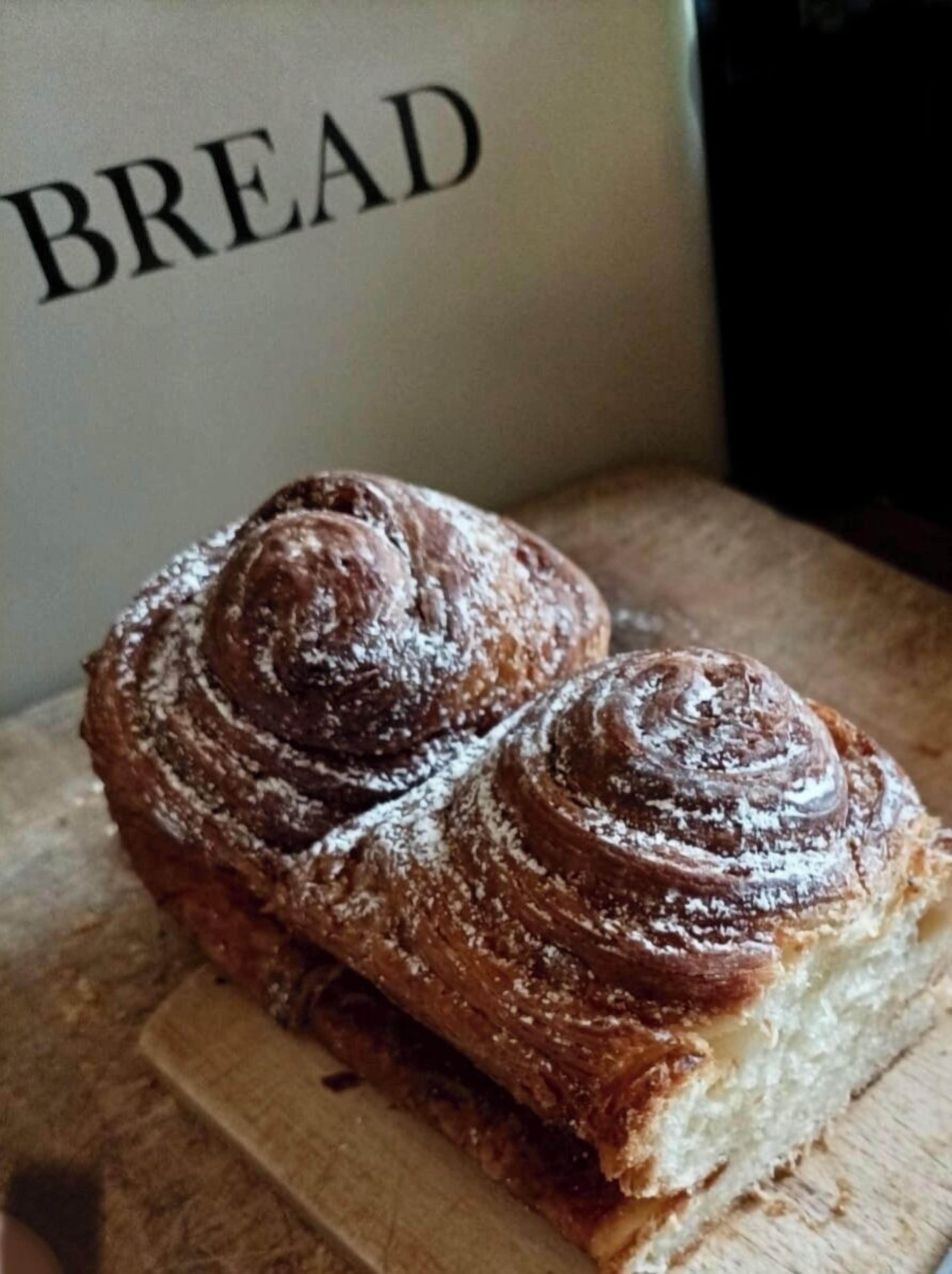 Dos pasteles sobre una tabla de madera, con un letrero que dice "BREAD" al fondo.