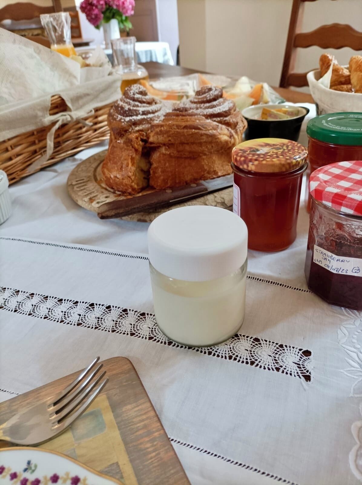 Aamiaispöydällä on leipää, lasi maitoa ja purkkeja hilloa.