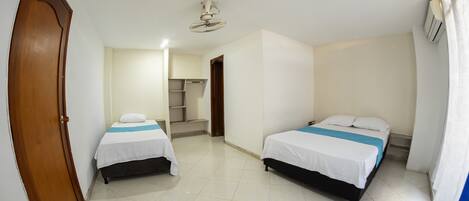 A room with two beds, a ceiling fan, and a door.