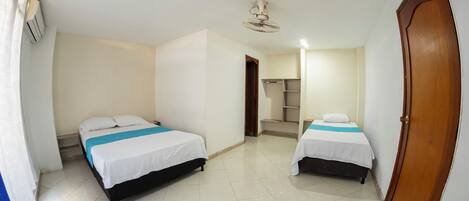 A room with two beds, a ceiling fan, and a door.