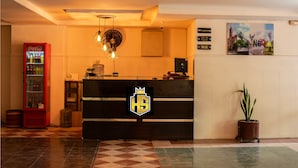 A reception desk with a logo, a Coca-Cola refrigerator, a potted plant, and a wall-mounted sign. - Hotel Santander Plaza (Neiva)