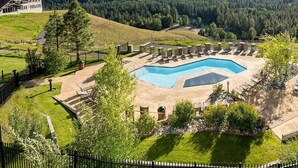 A resort with a swimming pool, lounge chairs, and a view of mountains. - Suncadia Penthouse with Mountain Views, Full Kitchen and Pool Hot Tub Access (Cle Elum)