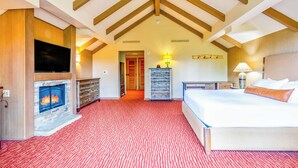 A hotel room with a fireplace, a bed, a TV, and a red carpeted floor. - Suncadia Penthouse with Mountain Views, Full Kitchen and Pool Hot Tub Access (Cle Elum)