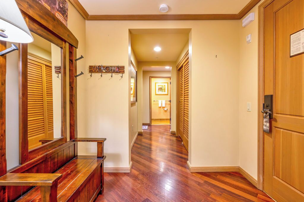 A hallway with wooden flooring, a bench, and a door on the right.