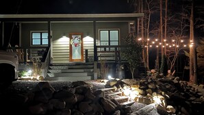 Ein Haus mit Veranda, einer Tür mit Kranz und Lichterkette.
