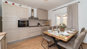 A modern kitchen with wooden cabinets, a built-in oven, and a dining area with a table set for four.