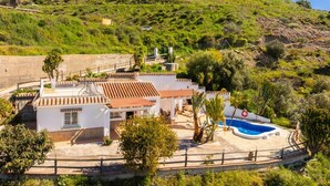 Eine Villa mit Swimmingpool, umgeben von Grünflächen und Hügeln.