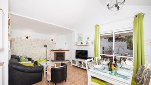 Ein Wohnzimmer mit Kamin, Fernseher, Essbereich mit Tisch und Stühlen sowie einer Steinwand.