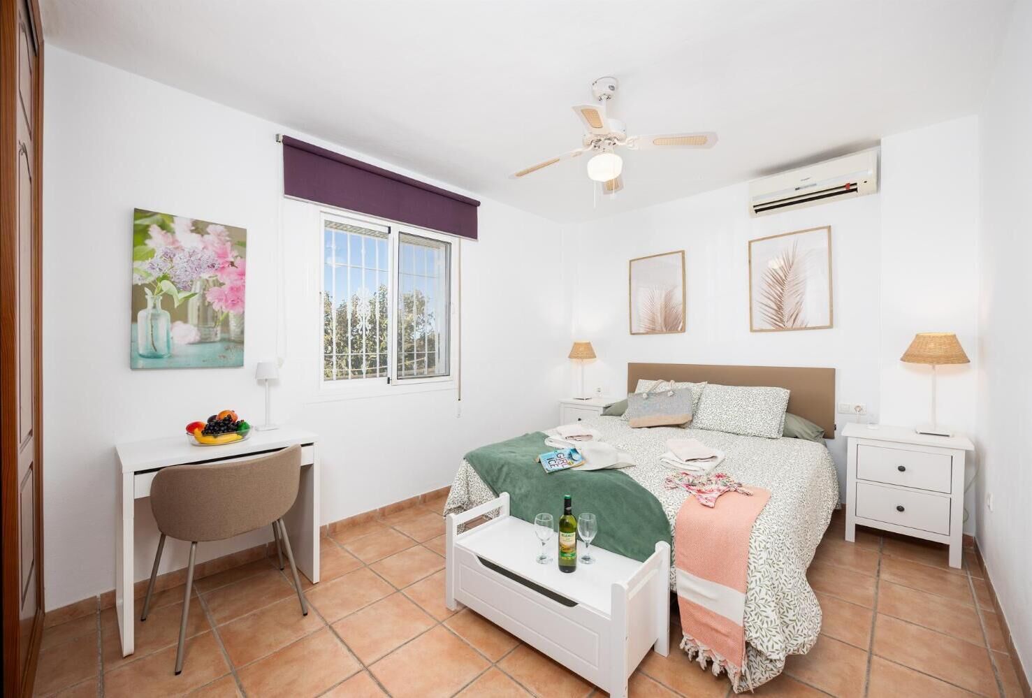 Une chambre à coucher comprenant un lit, un bureau, une chaise, des tables de chevet et une fenêtre.