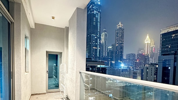 Un balcon avec vue sur la ville, de nuit.
