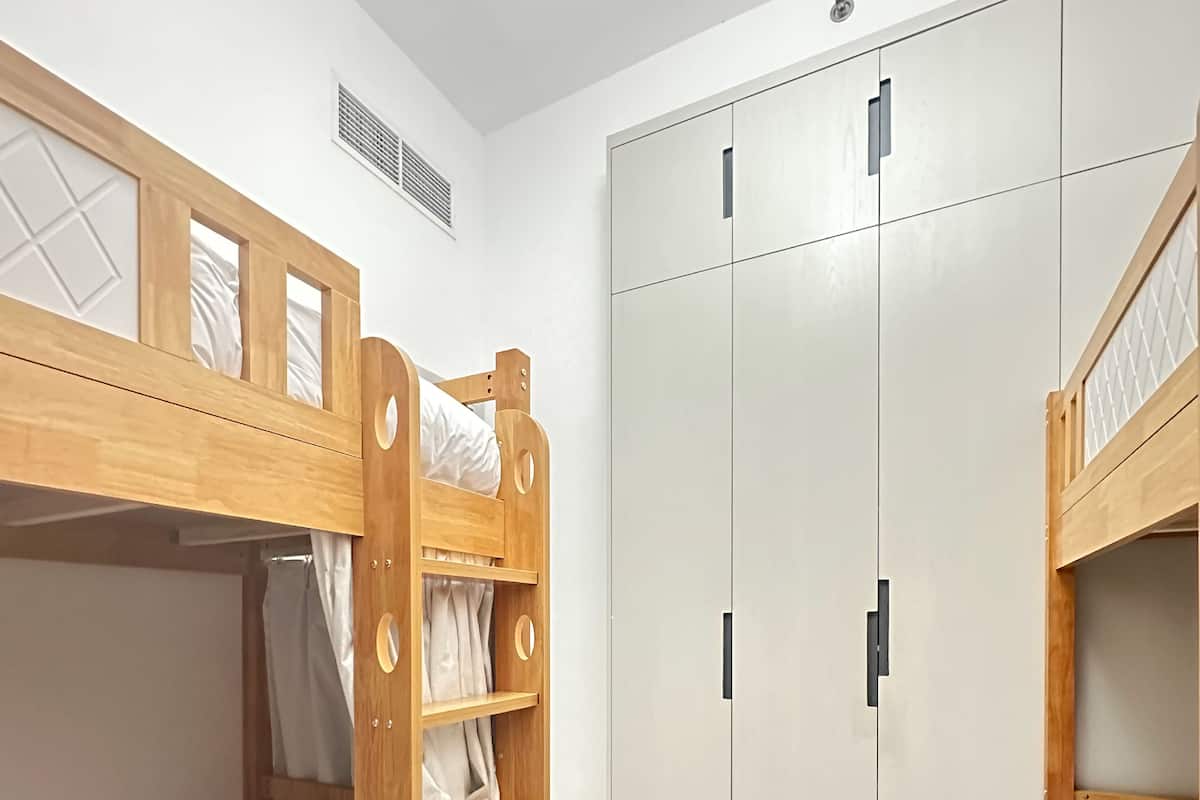 Une chambre avec des lits superposés, une armoire et une poubelle.