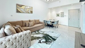 Un salon moderne comprenant un canapé, un fauteuil capitonné, une table à manger avec des chaises et un lustre.