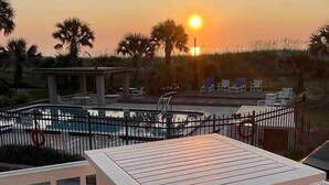 Ein Poolbereich mit Sonnenuntergangsblick, inklusive einem umzäunten Pool, Liegestühlen und einer Holzterrasse.