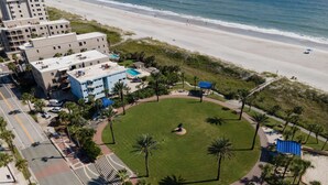 Ein Strandhotel mit einer zentralen Rasenfläche, Palmen und einem Poolbereich.