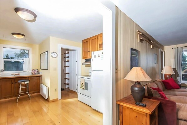 A compact living space with a kitchenette, a dining area, and a seating area with a sofa and lamps. - Hillside Cottage w/ Stunning Olympic Views & Deck (Sequim)