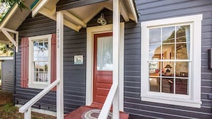 Une maison à deux étages avec une porte rouge, des fenêtres à cadre blanc et un porche doté d’une balustrade blanche.