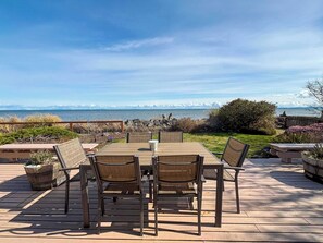 An outdoor patio with a table and chairs, overlooking a scenic view of the ocean and rocky coastline.
