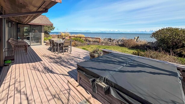 A wooden deck with a hot tub, a table with chairs, and a view of the ocean. - Waterfront, Hot tub, Pets OK, Sequim Dungeness (Sequim)