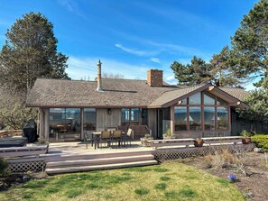 A house with a large deck, a chimney, and a covered patio area.