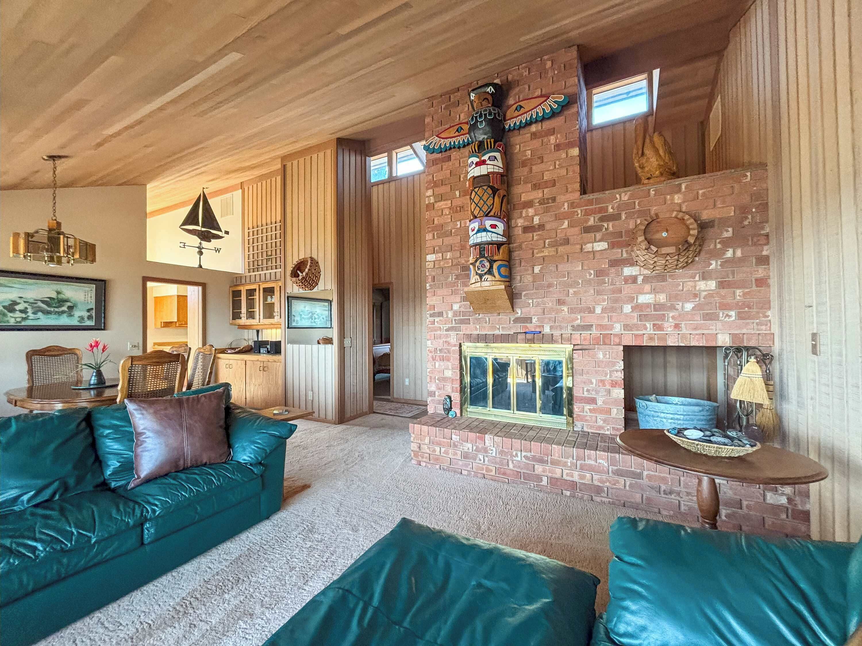 Un salon chaleureux avec une cheminée en briques, des éléments décoratifs en bois et un canapé en cuir vert.