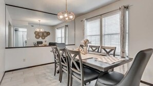 A dining area with a large mirror, a chandelier, and a table with chairs. - Charming 3-bedroom house in Shawnee with AC and WiFi (Shawnee)