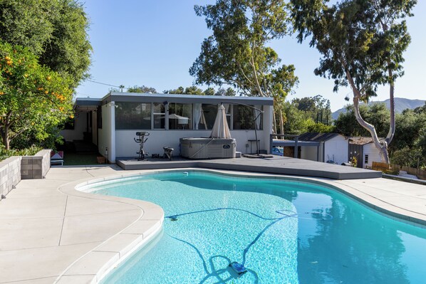 Una casa moderna con piscina, terraza cubierta y vistas al paisaje circundante.