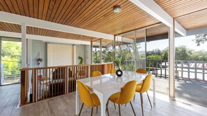 Un comedor amplio con techo de madera, ventanas grandes y vistas al exterior.