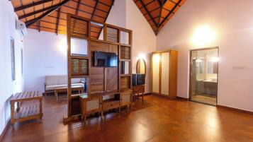 Una habitación amplia con techo alto, muebles de madera, televisor y armario.