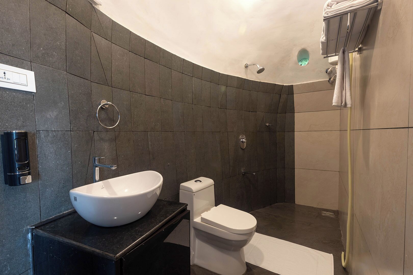 A modern bathroom with a freestanding sink, toilet, and shower.