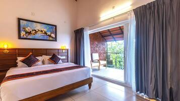 A hotel room with a large bed, a painting on the wall, a balcony with a chair, and curtains.