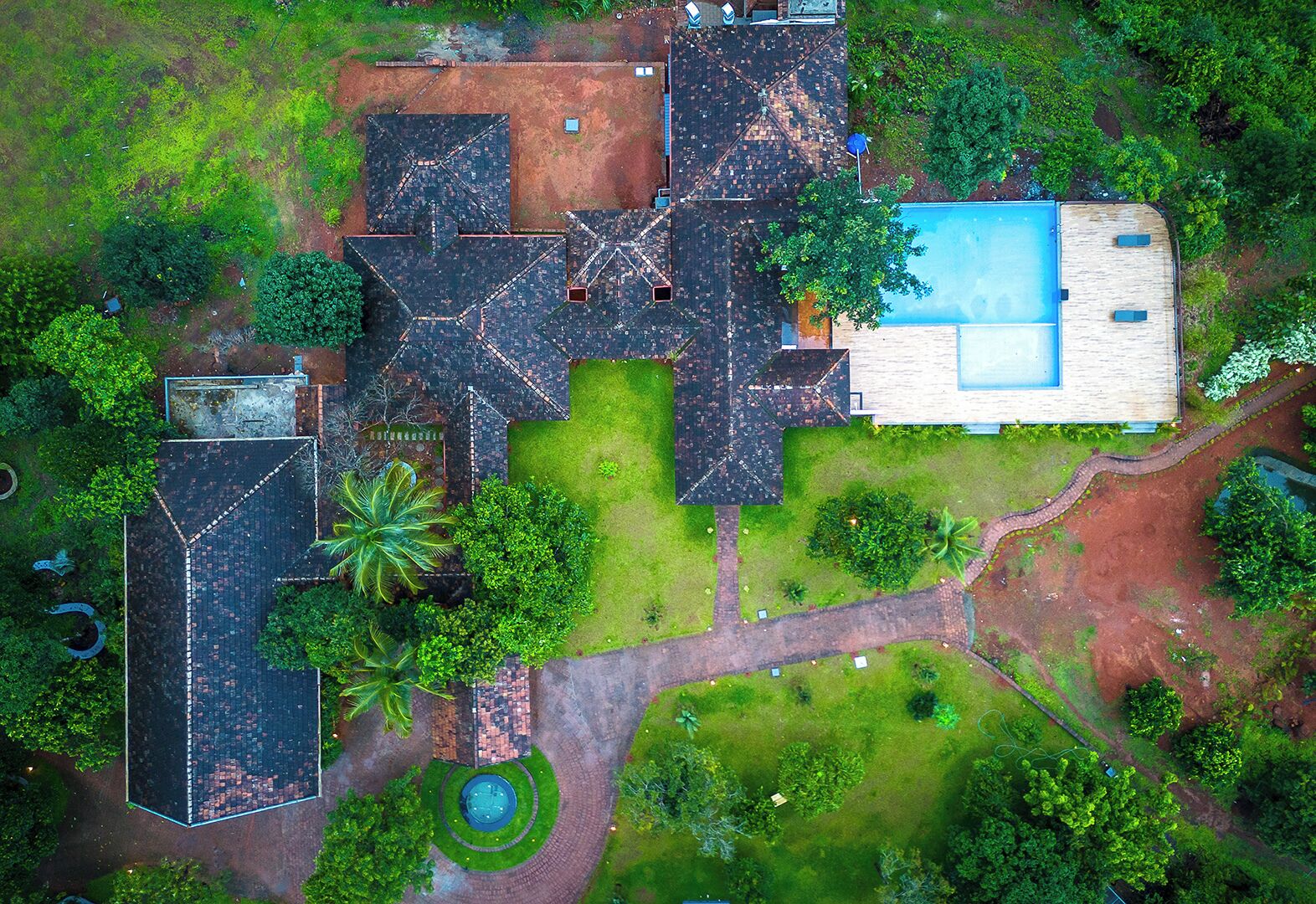 Vista aérea de un área residencial con varias casas, piscina y jardín circular.