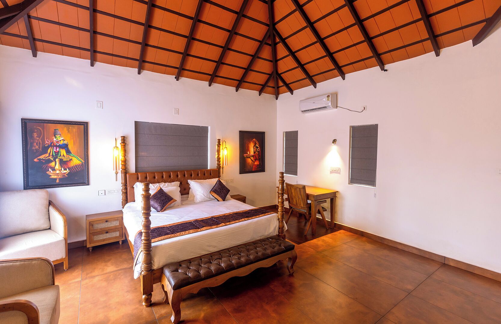 A bedroom with a bed, bedside tables, a bench, and artwork on the walls.