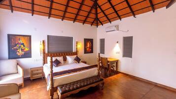 A bedroom with a bed, bedside tables, a bench, and artwork on the walls.