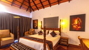 A spacious bedroom with a large bed, a wooden headboard, a bench, a chair, and a nightstand. - Sandal Mist Resort and spa  (Kasaragod)