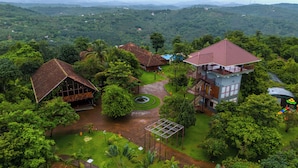 A resort with multiple buildings surrounded by lush greenery and a mountainous backdrop. - Sandal Mist Resort and spa  (Kasaragod)