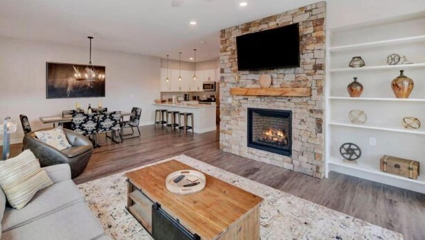 A modern living room with a fireplace, a dining area, and a kitchen in the background. - Aspen 2 Bedroom Condo at the Base of Aspen Mountain, Next to Lift 1A (Aspen)